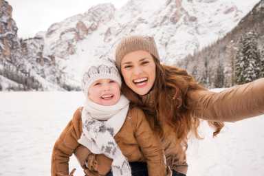 Mother and child taking selfie among snow-capped mountains