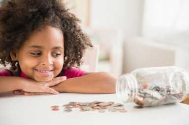 African American girl counting change in jar