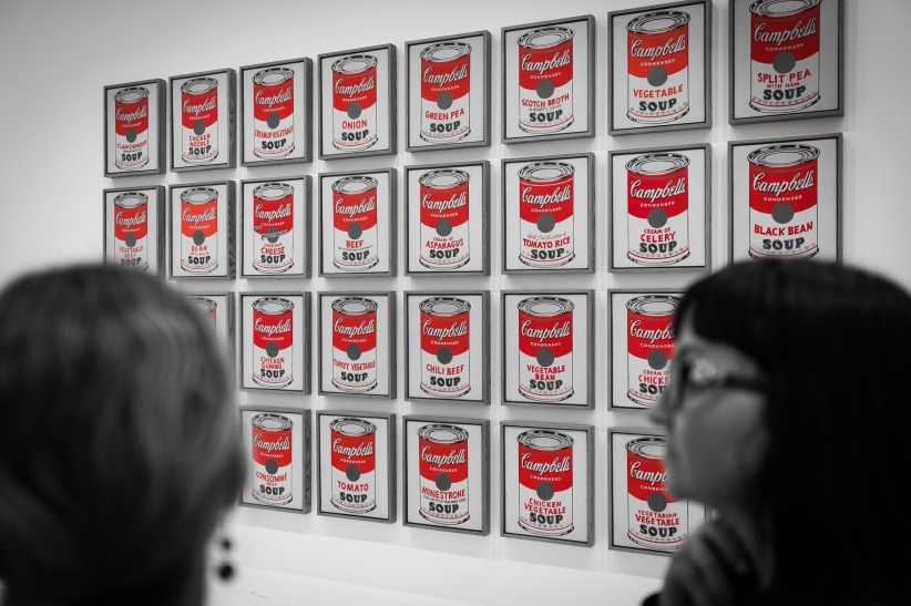 Museum visitors admiring Andy Warhol’s Campbell’s Soup Cans artwork—a grid of vintage soup can prints—at MoMA in black and white photography.