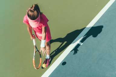 Young girl playing tennis, preparing to serve