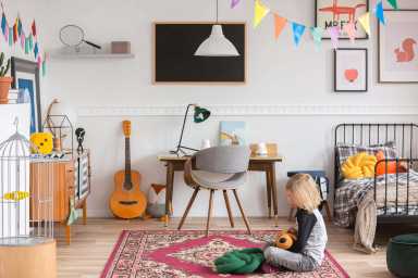 Little kid sitting on the rug in the white bedroom with vintage furniture