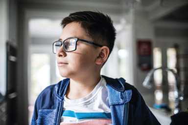 School age boy looking out window