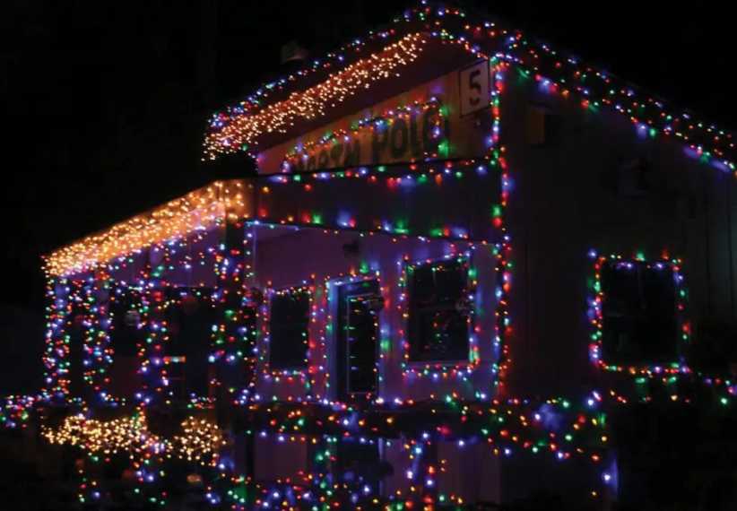 A house covered in vibrant, multicolored Christmas lights, glowing brightly in the dark night during a festive holiday celebration.