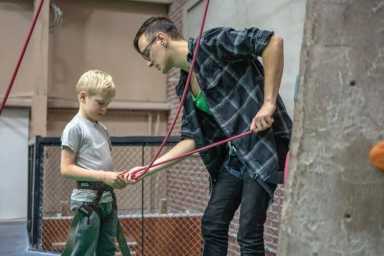 A person reaching up to grasp a climbing hold on an indoor rock-climbing wall.