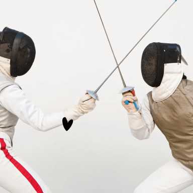 Two athletes clad in protective fencing gear and mesh masks engage in a duel, their swords crossing mid-air against a plain background.