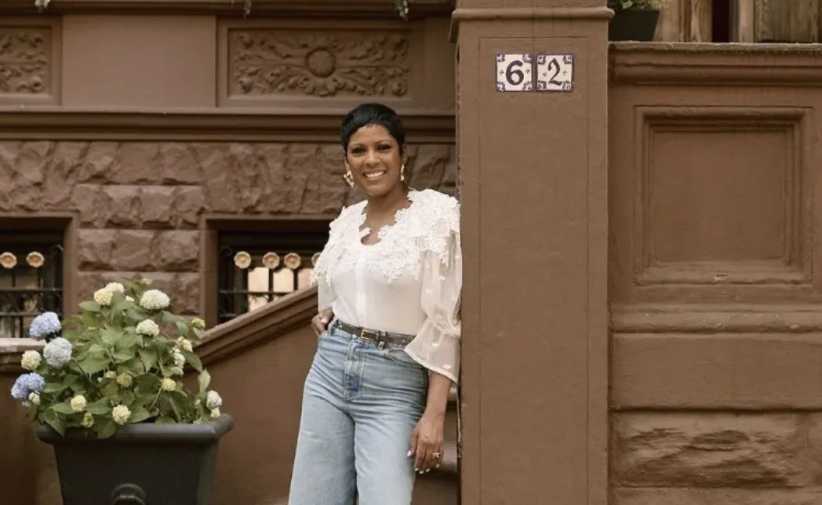 Tamron Hall leans on a post in front of her Harlem brownstone, son Moses in foreground.